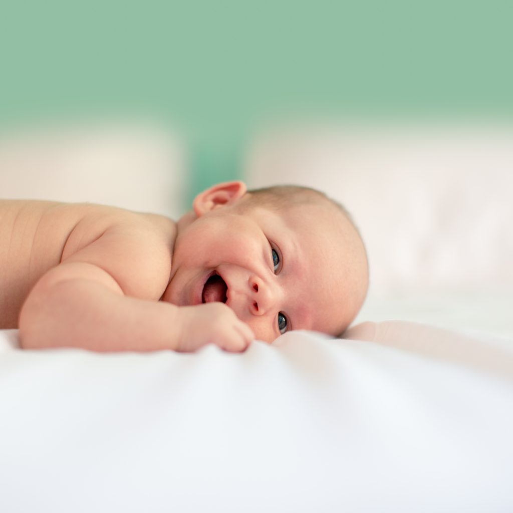 lachendes Baby liegt auf einer Decke